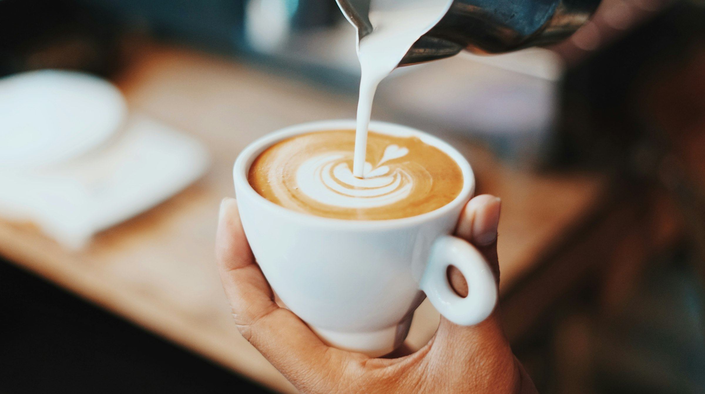 Barista pouring milk into a latte cup